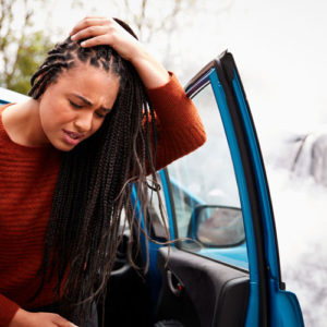 young woman clasps her head in pain after a car accident