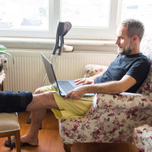 injured man works from home on his laptop