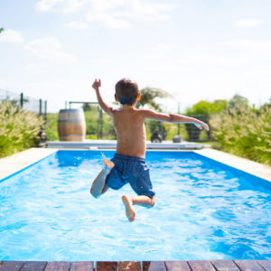 a young child jumps into a pool