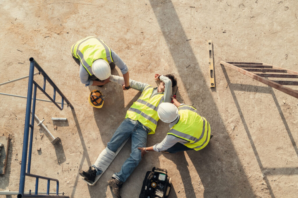 Construction team providing first aid to a coworker after a falling accident at a construction site.